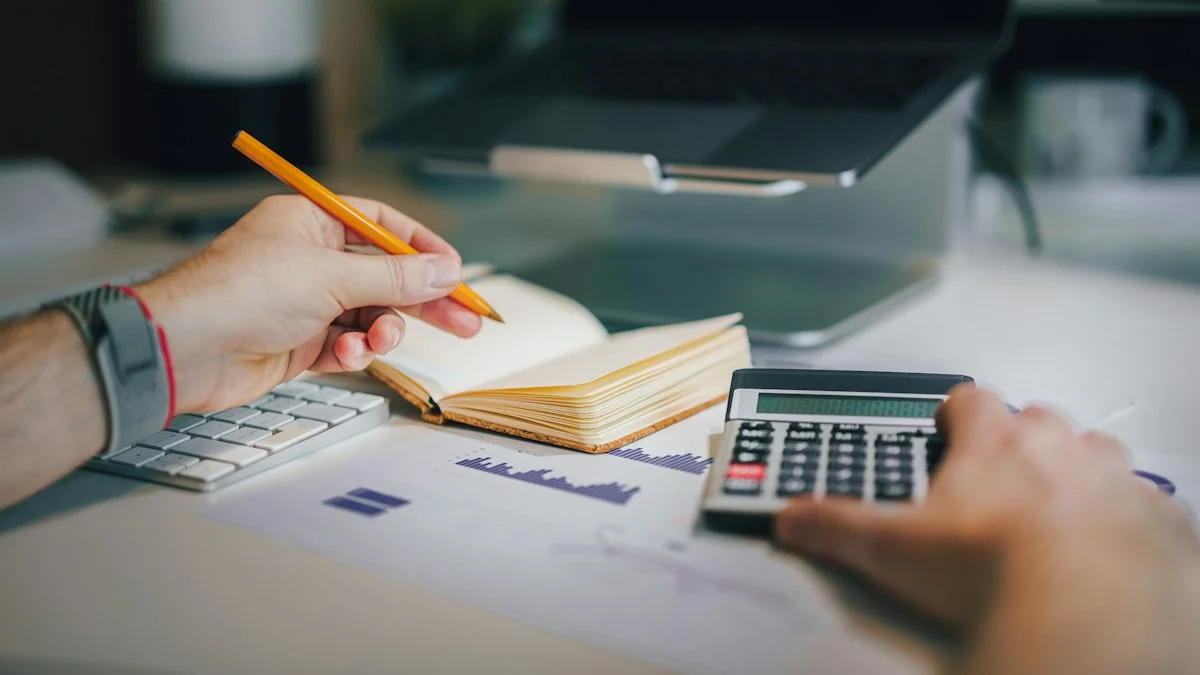 Hand with pencil and calculator working out hosting, domain and maintenance costs for a website
