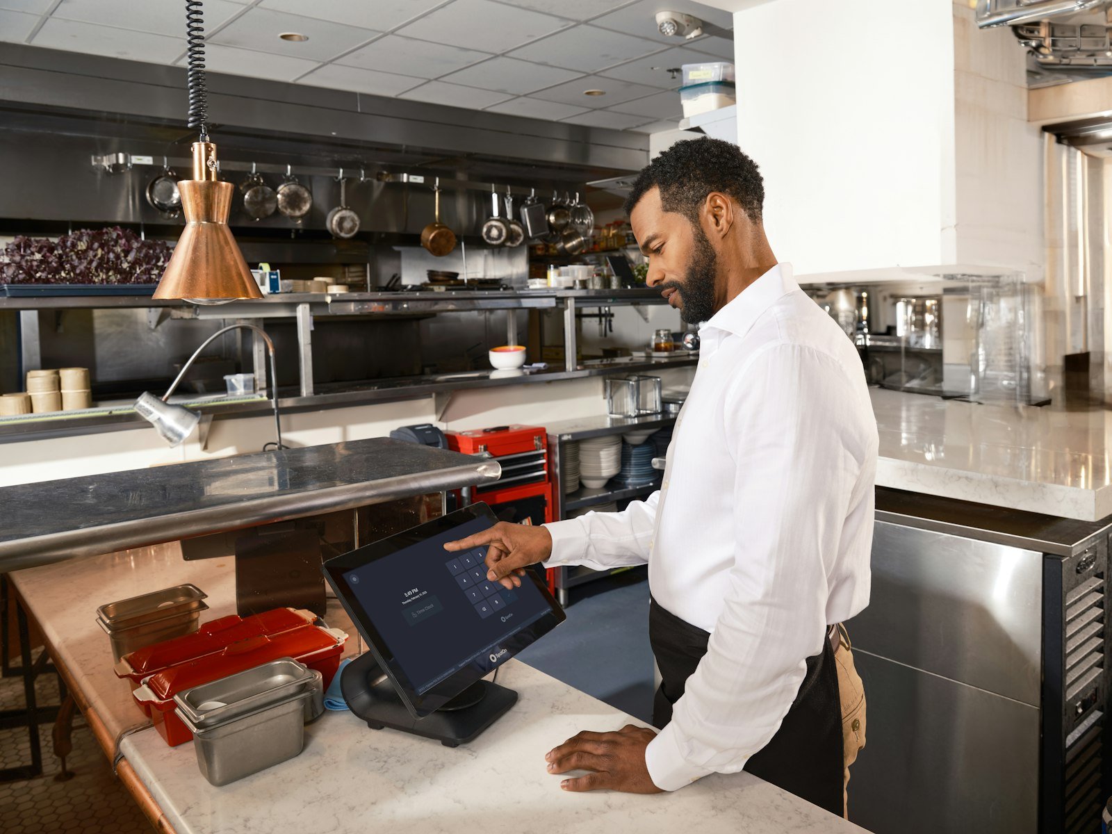 Restaurant staff member using an automated ordering touch screen in the kitchen