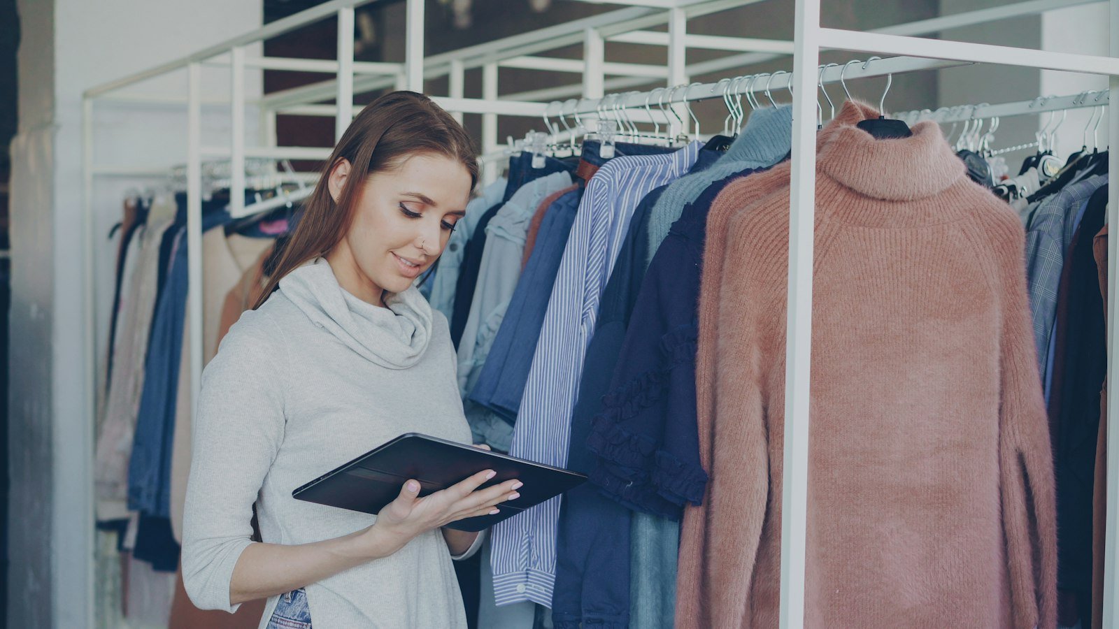 Boutique owner checking online orders on a tablet in her store